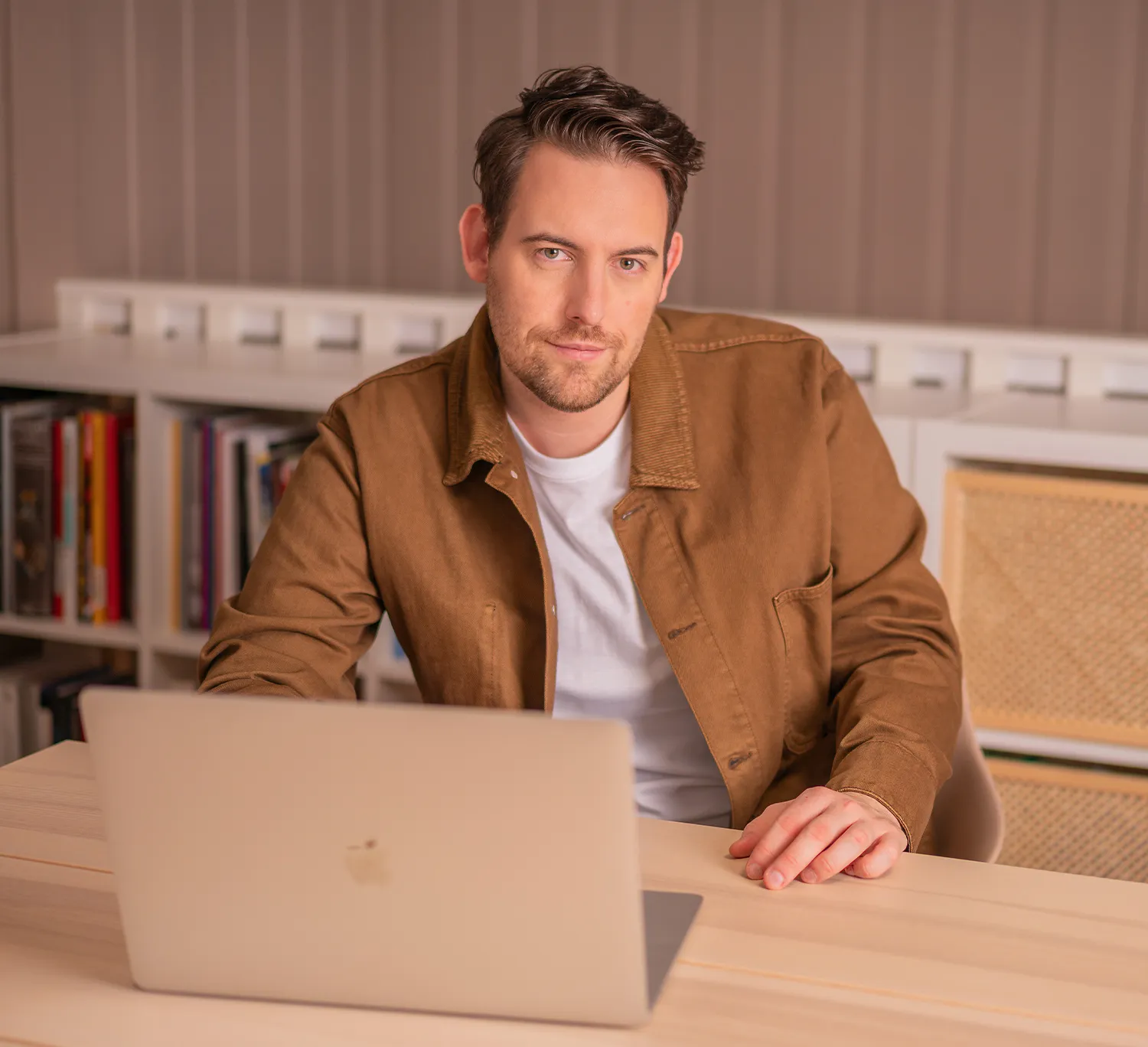 Bence Székely, brand strategy consultant, sitting at a desk working on a laptop in a brown blazer