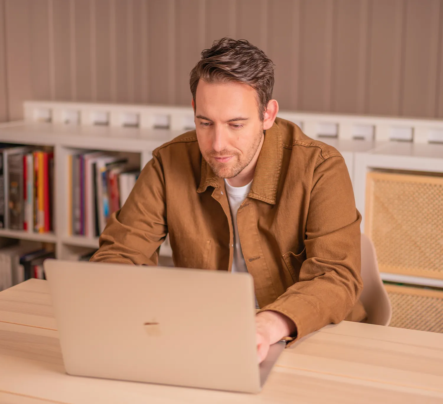 Bence Székely, annonseringskonsulent, jobber på en laptop i en brun jakke